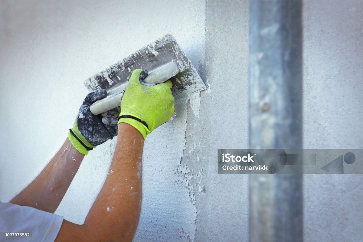 Handwerker trägt Putz an einer Fassade auf